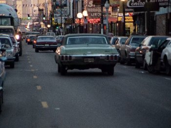 Movie still from “Henry: Portrait of a Serial Killer” (1986), directed by John McNaughton – Cars are driving down a busy city street at night; Extreme Wide shot, High angle