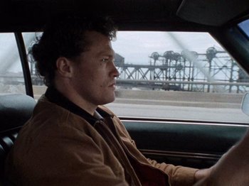 Movie still from “Henry: Portrait of a Serial Killer” (1986), directed by John McNaughton – A man sitting in the driver's seat of a car; Close Up shot, Low angle