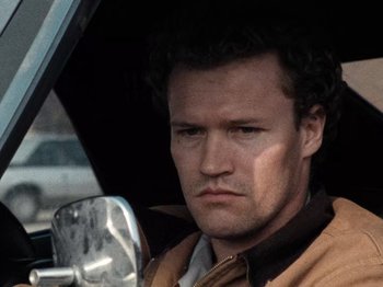 Movie still from “Henry: Portrait of a Serial Killer” (1986), directed by John McNaughton – A person sitting in a car; Close Up shot, Low angle