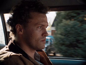 Movie still from “Henry: Portrait of a Serial Killer” (1986), directed by John McNaughton – A person sitting in a car looking out of the window; Close Up shot, Low angle