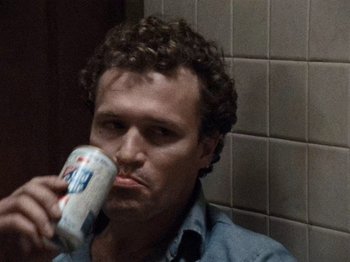 Movie still from “Henry: Portrait of a Serial Killer” (1986), directed by John McNaughton – A man drinking a can of beer in a bathroom; Close Up shot, High angle