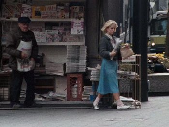 Movie still from “Henry: Portrait of a Serial Killer” (1986), directed by John McNaughton – A woman walking down the street with a dog in her hand; Wide shot, High angle
