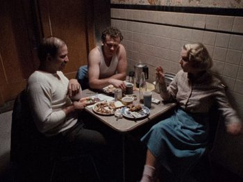 Movie still from “Henry: Portrait of a Serial Killer” (1986), directed by John McNaughton – A group of people sitting at a table eating food; Wide shot, High angle
