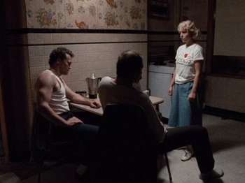Movie still from “Henry: Portrait of a Serial Killer” (1986), directed by John McNaughton – A group of people sitting at a table in a room; Wide shot, High angle