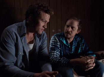 Movie still from “Henry: Portrait of a Serial Killer” (1986), directed by John McNaughton – Two men are sitting in a dark room; Medium shot, Over the shoulder angle