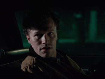 Movie still from “Henry: Portrait of a Serial Killer” (1986), directed by John McNaughton – A man sitting in the back seat of a car at night; Close Up shot, Over the shoulder angle