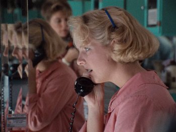 Movie still from “Henry: Portrait of a Serial Killer” (1986), directed by John McNaughton – A woman talking on a phone in front of a mirror; Close Up shot, High angle