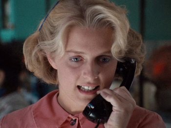 Movie still from “Henry: Portrait of a Serial Killer” (1986), directed by John McNaughton – A woman talking on a phone while wearing a pink shirt; Close Up shot, Low angle