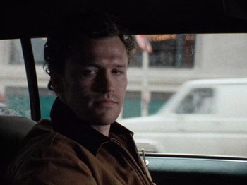 Movie still from “Henry: Portrait of a Serial Killer” (1986), directed by John McNaughton – A man sitting in the back seat of a car looking out the window; Close Up shot, Low angle
