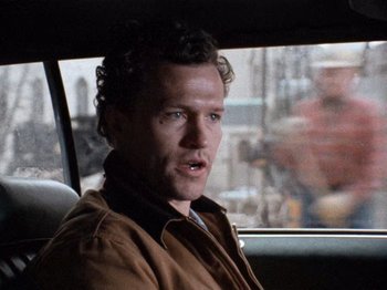 Movie still from “Henry: Portrait of a Serial Killer” (1986), directed by John McNaughton – A man sitting in the back seat of a car; Close Up shot, Over the shoulder angle