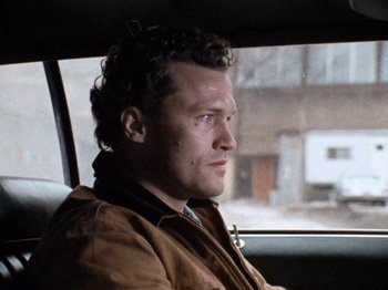 Movie still from “Henry: Portrait of a Serial Killer” (1986), directed by John McNaughton – A man sitting in the back seat of a car; Close Up shot, Over the shoulder angle