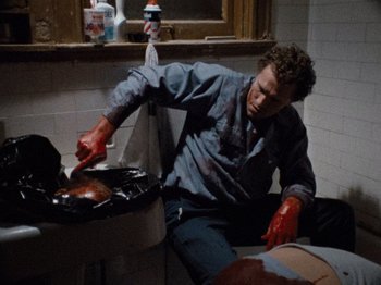 Movie still from “Henry: Portrait of a Serial Killer” (1986), directed by John McNaughton – A man wearing red gloves cooking food on a grill; Medium shot, High angle