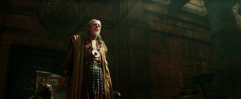 Movie still from “Hercules” (2014), directed by Brett Ratner – An old man dressed as a roman soldier in front of a brick wall; Medium shot, Low angle