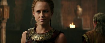 Movie still from “Hercules” (2014), directed by Brett Ratner – A woman in a gold and black outfit looking at the camera; Close Up shot, Over the shoulder angle