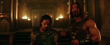 Movie still from “Hercules” (2014), directed by Brett Ratner – A man and a woman in roman garb standing in front of a fire pit; Medium shot, Over the shoulder angle