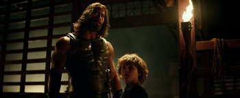 Movie still from “Hercules” (2014), directed by Brett Ratner – A man and a boy are standing next to each other; Medium shot, Over the shoulder angle