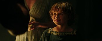 Movie still from “Hercules” (2014), directed by Brett Ratner – A young boy is smiling in front of an older woman; Close Up shot, Over the shoulder angle