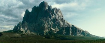 A large rock formation in the middle of a green field