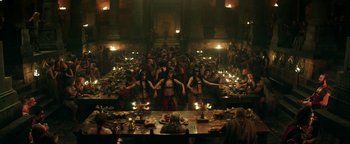 Movie still from “Hercules” (2014), directed by Brett Ratner – A group of people standing around a table with food; Extreme Wide shot, High angle