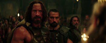Movie still from “Hercules” (2014), directed by Brett Ratner – A group of men standing next to each other in a room; Close Up shot, Over the shoulder angle