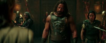 Movie still from “Hercules” (2014), directed by Brett Ratner – A man with a muscular body and a leather vest; Medium shot, Over the shoulder angle