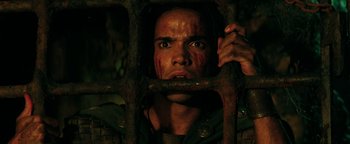 Movie still from “Hercules” (2014), directed by Brett Ratner – A man with blood all over his face looking through bars; Close Up shot, Overhead angle