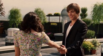 Movie still from “High School Musical 3: Senior Year” (2008), directed by Kenny Ortega – A man and a woman shaking hands in front of a building; Medium shot, Over the shoulder angle
