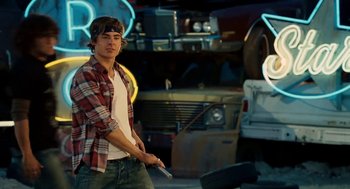 Movie still from “High School Musical 3: Senior Year” (2008), directed by Kenny Ortega – A young man holding a knife in his hand; Medium shot, Over the shoulder angle