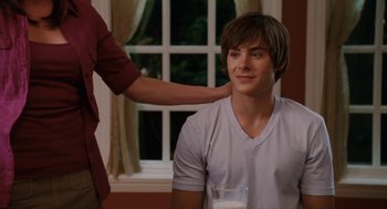 Movie still from “High School Musical 3: Senior Year” (2008), directed by Kenny Ortega – A woman is helping a young man drink milk; Medium shot, Over the shoulder angle