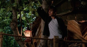 Movie still from “High School Musical 3: Senior Year” (2008), directed by Kenny Ortega – A man standing next to a tree with a lantern; Wide shot, Low angle