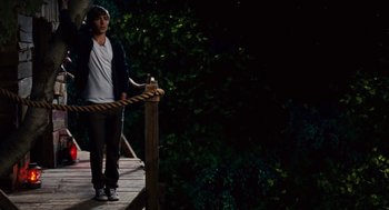 Movie still from “High School Musical 3: Senior Year” (2008), directed by Kenny Ortega – A young man standing on a wooden bridge holding a rope; Wide shot, High angle