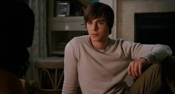 Movie still from “High School Musical 3: Senior Year” (2008), directed by Kenny Ortega – A young man sitting in front of a fire place; Medium shot, Over the shoulder angle