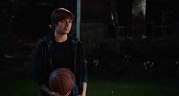 Movie still from “High School Musical 3: Senior Year” (2008), directed by Kenny Ortega – A young man holding a basketball in his hands; Medium shot, Over the shoulder angle