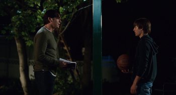 Movie still from “High School Musical 3: Senior Year” (2008), directed by Kenny Ortega – A man and a woman standing next to each other holding a basketball; Medium shot, Over the shoulder angle