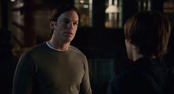 Movie still from “High School Musical 3: Senior Year” (2008), directed by Kenny Ortega – A man standing next to another man in a dark room; Close Up shot, Over the shoulder angle