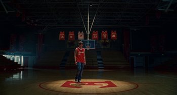 Movie still from “High School Musical 3: Senior Year” (2008), directed by Kenny Ortega – A man standing on a basketball court in front of a court; Wide shot, Low angle