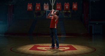 Movie still from “High School Musical 3: Senior Year” (2008), directed by Kenny Ortega – A man holding a basketball on top of a basketball court; Wide shot, Low angle