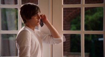 Movie still from “High School Musical 3: Senior Year” (2008), directed by Kenny Ortega – A man holding a cell phone up to his ear; Medium shot, Over the shoulder angle