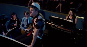 Movie still from “High School Musical 3: Senior Year” (2008), directed by Kenny Ortega – A young man wearing a white hat sitting next to a piano; Medium shot, Over the shoulder angle