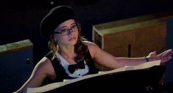 Movie still from “High School Musical 3: Senior Year” (2008), directed by Kenny Ortega – A woman wearing a black hat and glasses playing a piano; Medium shot, Low angle