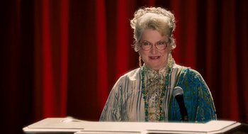 Movie still from “High School Musical 3: Senior Year” (2008), directed by Kenny Ortega – An older woman wearing a wig and a long dress; Medium shot, Low angle