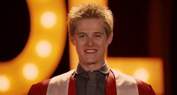 Movie still from “High School Musical 3: Senior Year” (2008), directed by Kenny Ortega – A man with blonde hair and a gray shirt; Close Up shot, Low angle