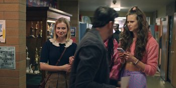 Movie still from “Honor Society” (2022), directed by Oran Zegman – A group of young people standing around each other in a room; Medium shot, Over the shoulder angle