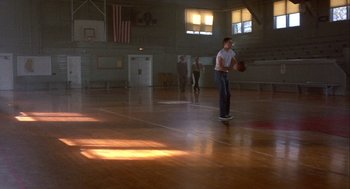 Movie still from “Hoosiers” (1986), directed by David Anspaugh – A man is playing basketball in a gymnasium; Wide shot, Low angle