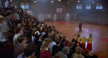 Movie still from “Hoosiers” (1986), directed by David Anspaugh – A crowd of people sitting in front of a microphone; Wide shot, High angle