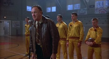 Movie still from “Hoosiers” (1986), directed by David Anspaugh – A group of men standing next to each other in a gym; Medium shot, Low angle