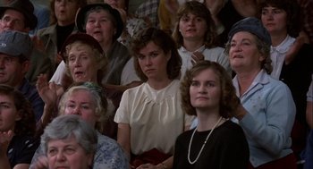 Movie still from “Hoosiers” (1986), directed by David Anspaugh – A group of women sitting in a crowd watching a performance; Medium shot, High angle