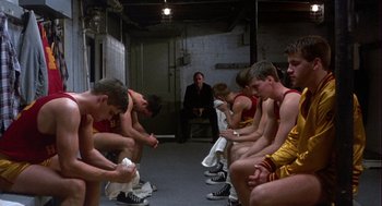 Movie still from “Hoosiers” (1986), directed by David Anspaugh – A group of young men sitting on a bench; Wide shot, Low angle