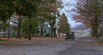 Movie still from “Hoosiers” (1986), directed by David Anspaugh – An old truck is parked on the side of the road in front of a house; Extreme Wide shot, High angle