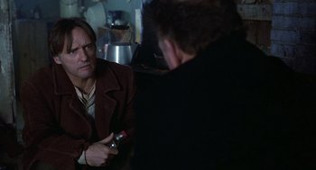 Movie still from “Hoosiers” (1986), directed by David Anspaugh – A man in a brown jacket is talking to another man in a black jacket; Close Up shot, Over the shoulder angle